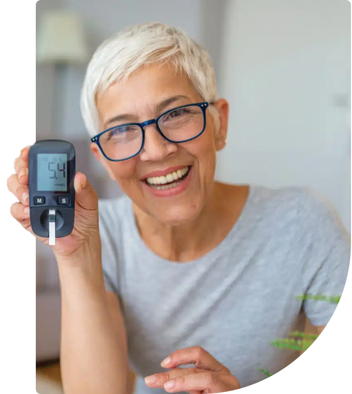 A smiling woman showing a glucose monitor reading of normal