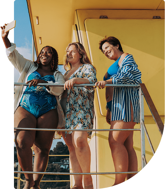 A group of happy women taking selfies at the beach
