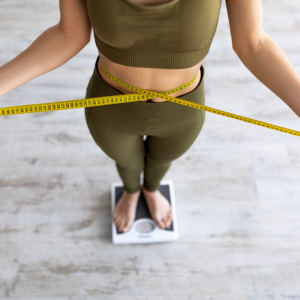 woman weighing herself concerned with her weight management